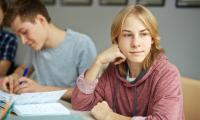 I gymnasiet: To drenge med en bog foran sig, den ene dagdrømmende
