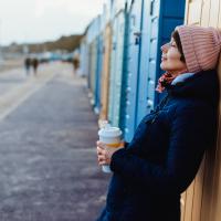 Billede af kvinde med kaffe ved strandpromonade